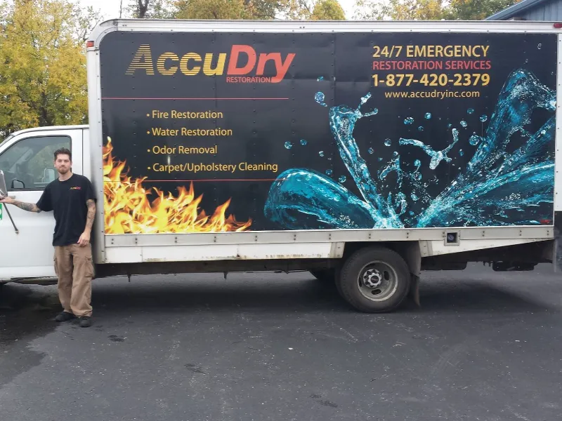 Man standing next to a white restoration service truck with fire and water graphics on the side.