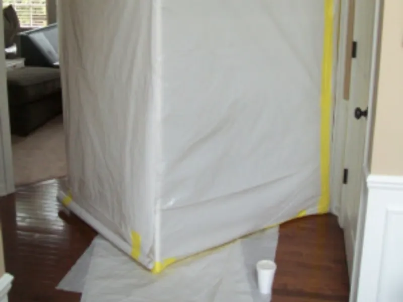 A plastic containment tent sealed with yellow tape inside a house hallway.